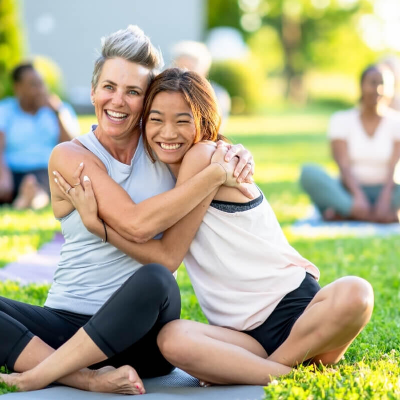 Two women laughing and hugging after a bridal yoga session in Lisbon